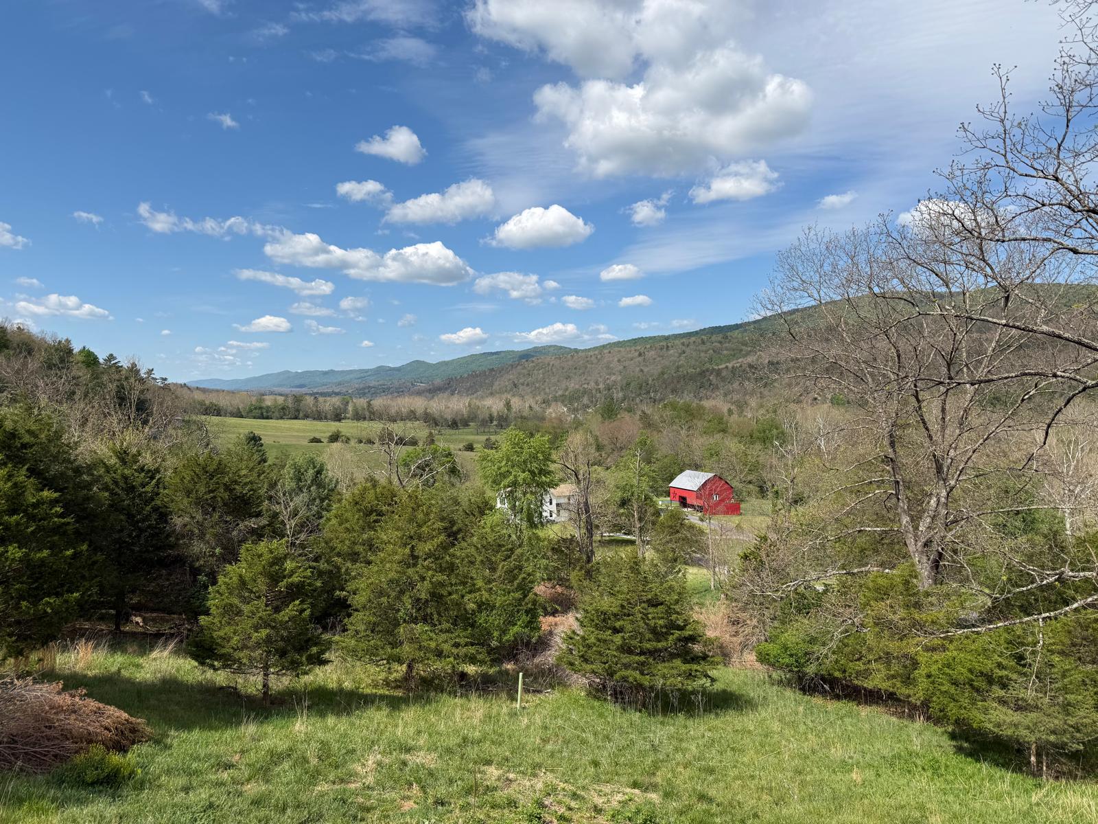 Green mountainside view with red barn in the distance